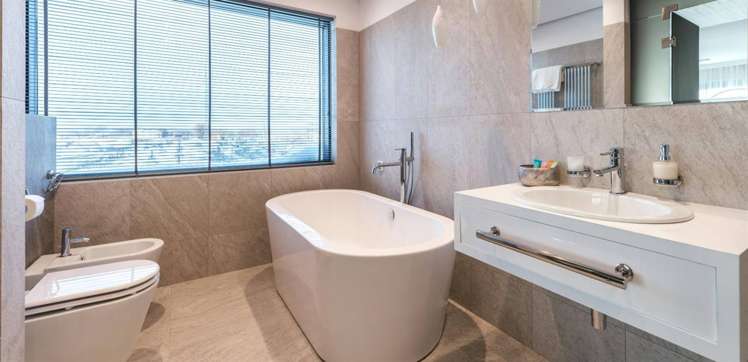 Modernes Badezimmer mit freistehender Wanne, Waschtisch und großformatigen Fliesen